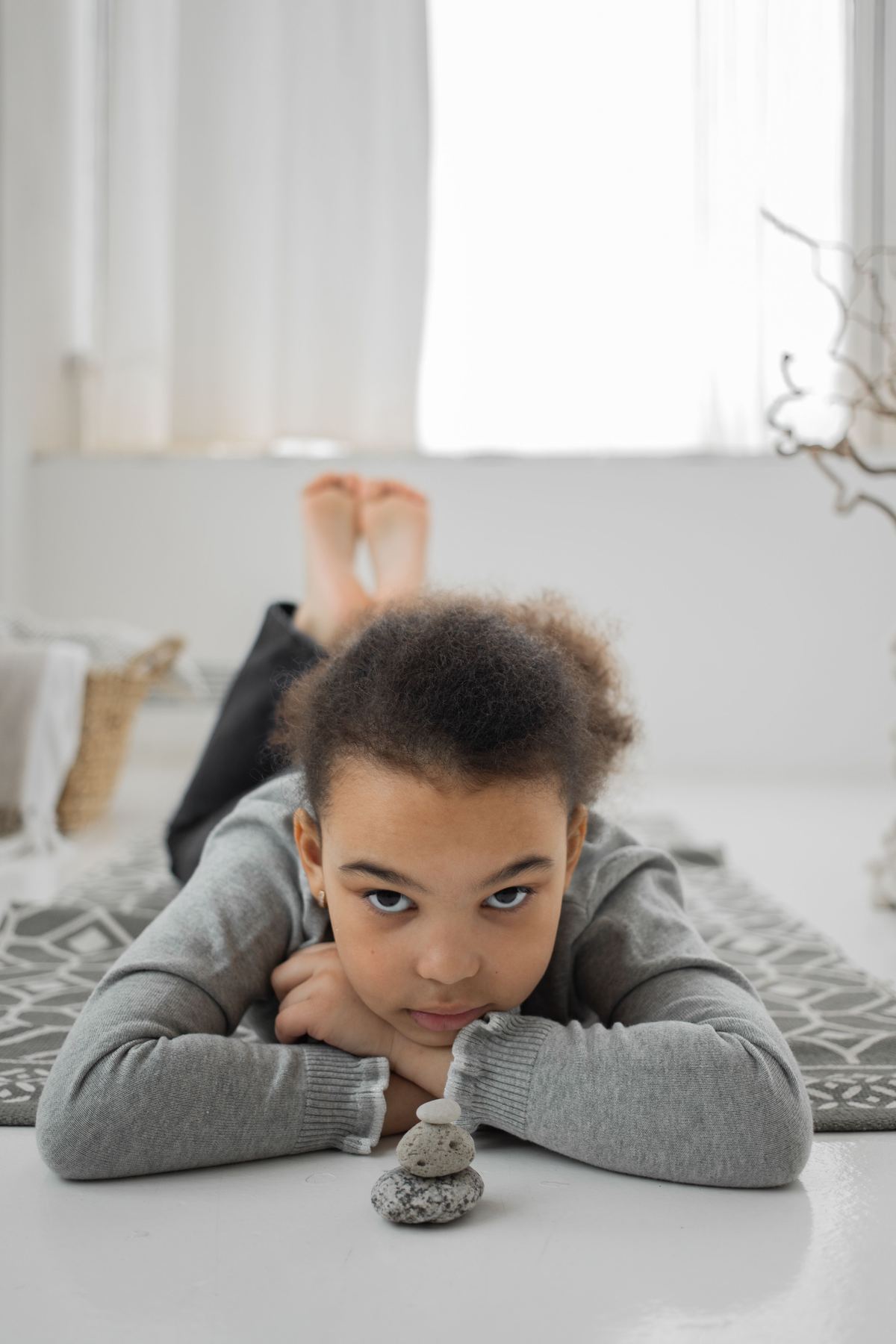 Niña concentrada y en calma junto a piedras apiladas en equilibrio