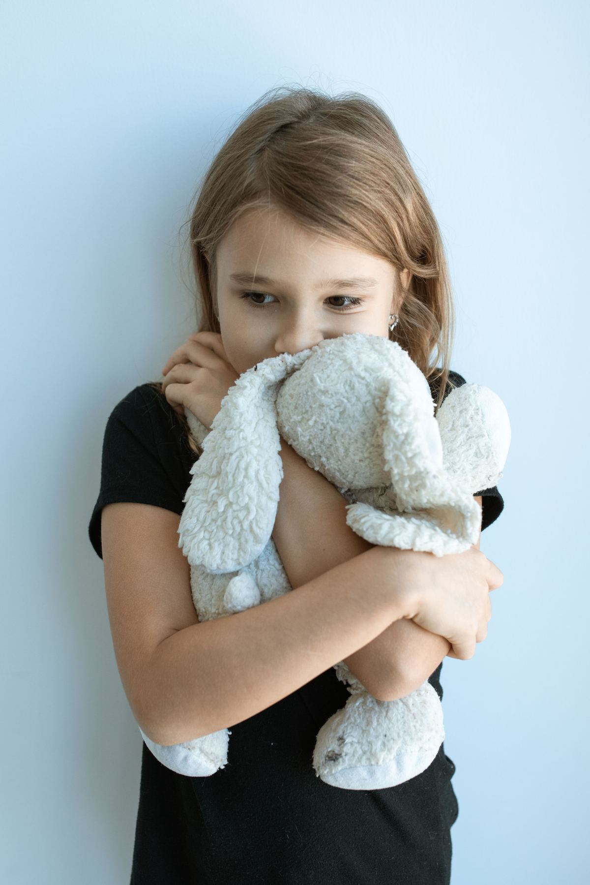 Niña abrazando fuerte un peluche, con expresión preocupada